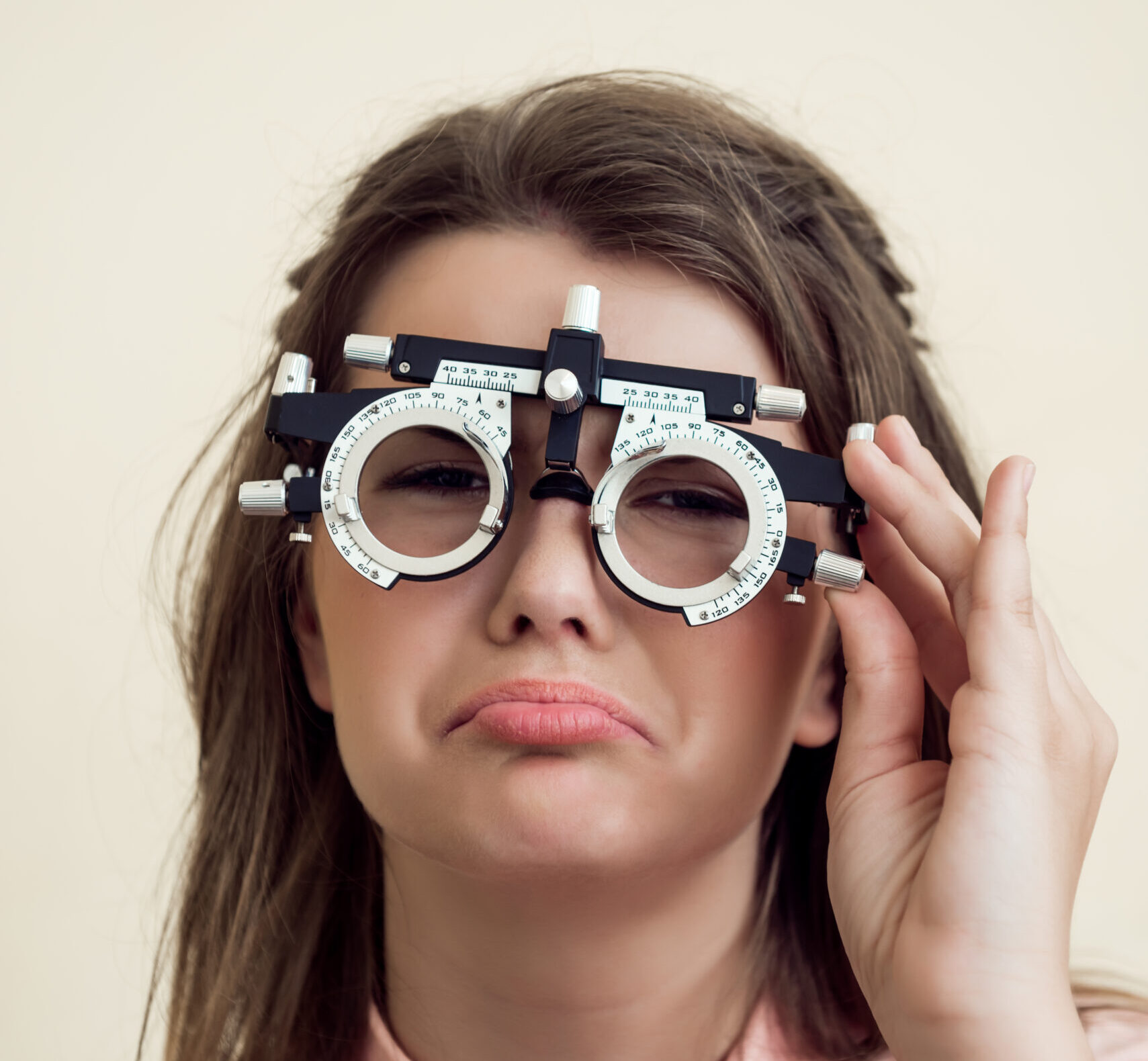 Sad girl has eye problems. Portrait of upset gloomy european woman in ophthalmologist office, testing vision while sitting and wearing phoropter, regretting that she spoilt sight near computer.